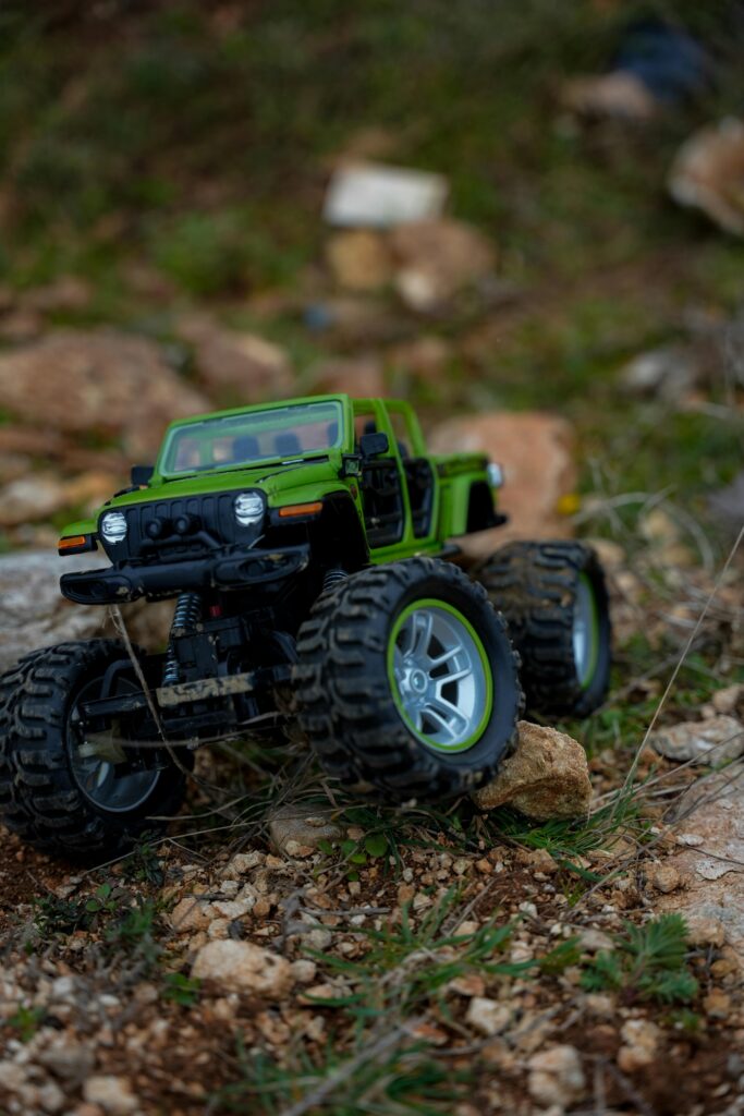 A green toy monster truck climbing over rocks, illustrating adventure and rugged play.